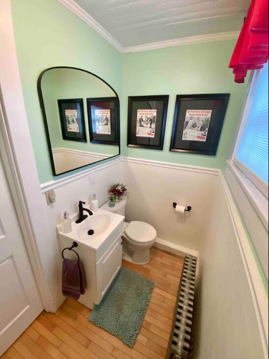 bathroom with hardwood / wood-style floors, crown molding, vanity, and toilet