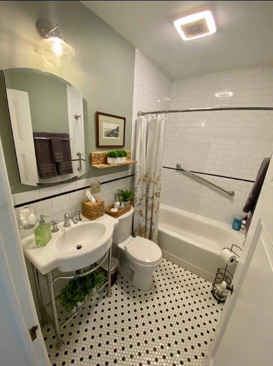 full bathroom featuring tile walls, shower / bath combo, sink, tile patterned floors, and toilet