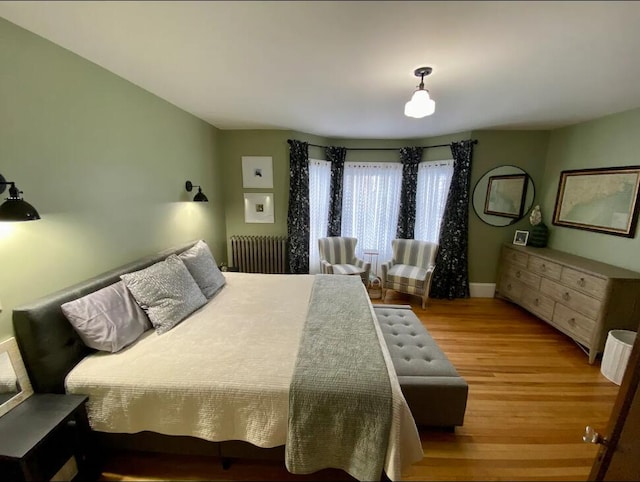 bedroom featuring radiator heating unit and wood-type flooring