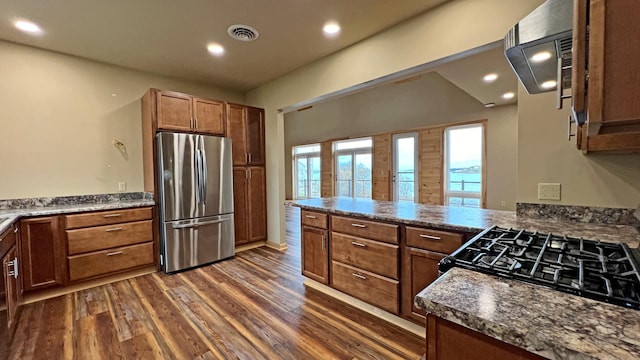 kitchen with stove, stainless steel fridge, kitchen peninsula, dark wood-type flooring, and vaulted ceiling