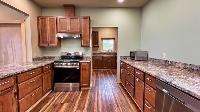 kitchen featuring appliances with stainless steel finishes, sink, stone counters, and dark hardwood / wood-style flooring