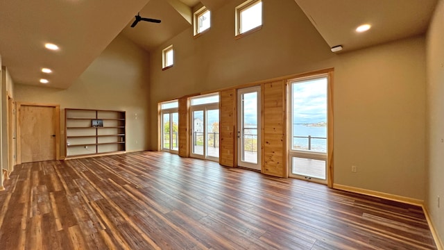 unfurnished living room with high vaulted ceiling, ceiling fan, and dark wood-type flooring