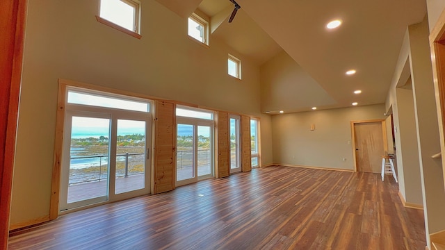 spare room featuring a towering ceiling and dark hardwood / wood-style floors