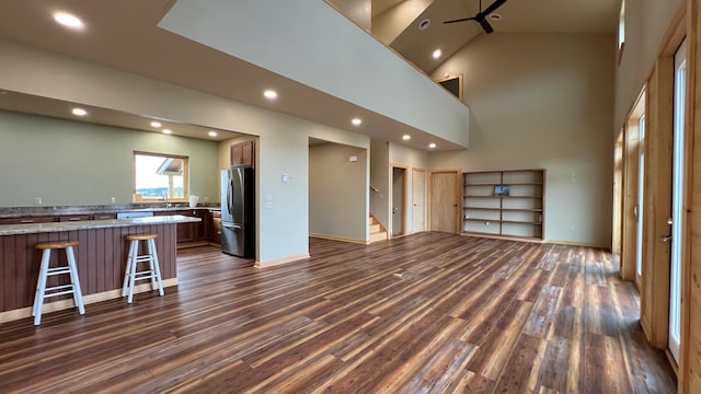 unfurnished living room with ceiling fan, dark hardwood / wood-style floors, and high vaulted ceiling