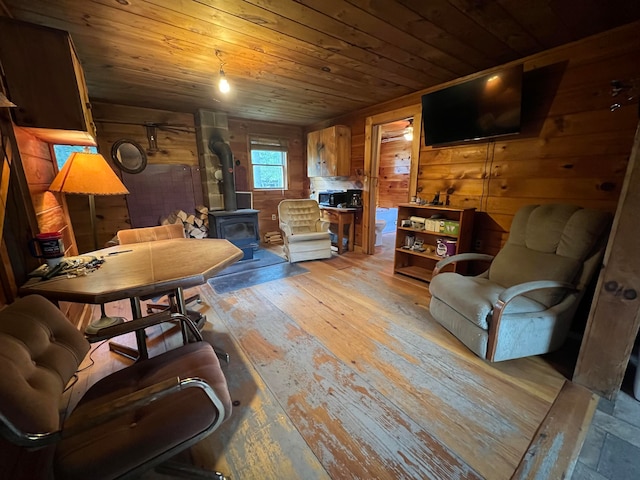 living room featuring a wood stove, wood walls, wooden ceiling, and light wood-type flooring