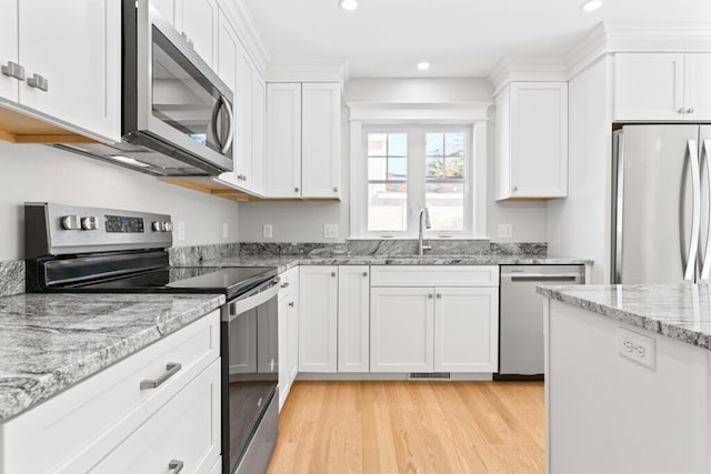 kitchen with light wood-type flooring, white cabinetry, appliances with stainless steel finishes, and sink