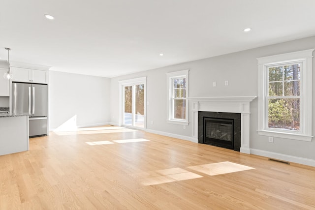 unfurnished living room featuring light wood-type flooring and a high end fireplace