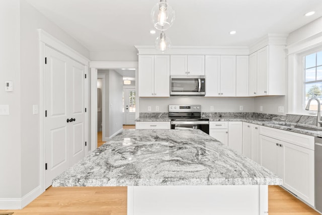 kitchen featuring white cabinets, light hardwood / wood-style floors, appliances with stainless steel finishes, and a kitchen island