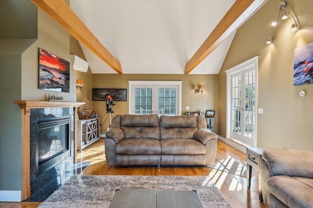 living room with french doors, vaulted ceiling with beams, hardwood / wood-style flooring, and a premium fireplace