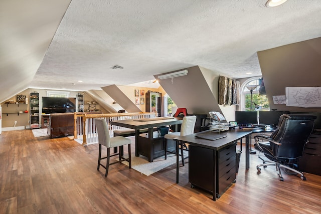 home office featuring a healthy amount of sunlight, vaulted ceiling, hardwood / wood-style floors, and a textured ceiling