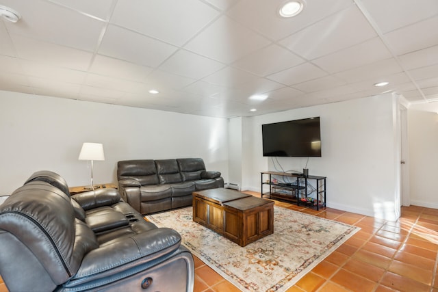 tiled living room with a baseboard radiator and a drop ceiling