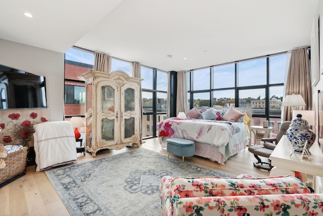 bedroom with light hardwood / wood-style floors and a wall of windows