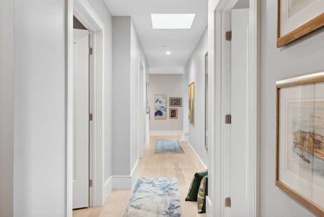 hall with light hardwood / wood-style flooring and a skylight