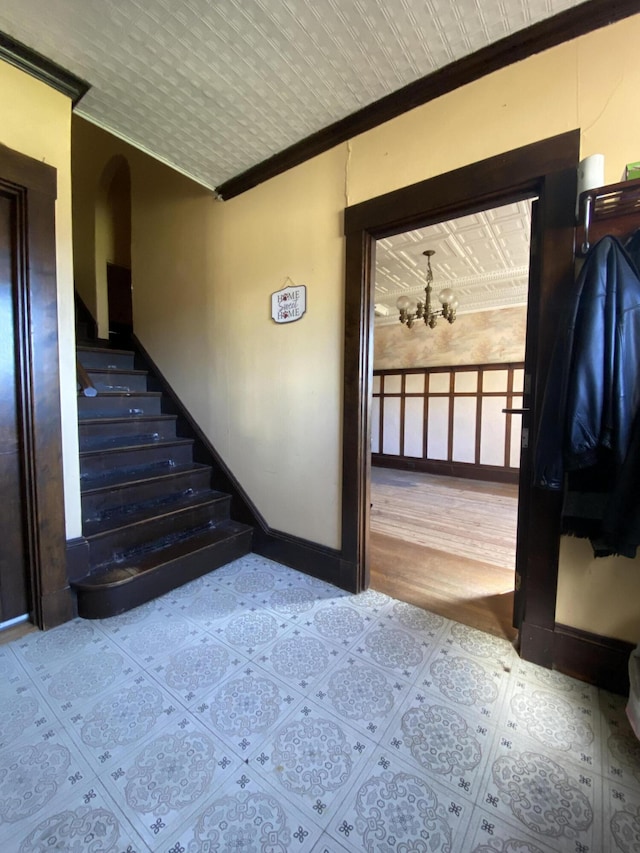 stairs with a chandelier, hardwood / wood-style flooring, and crown molding