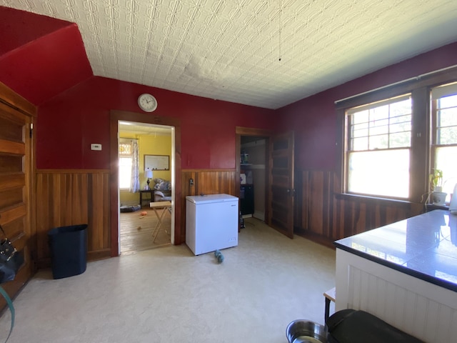 interior space featuring wood walls, light colored carpet, and refrigerator