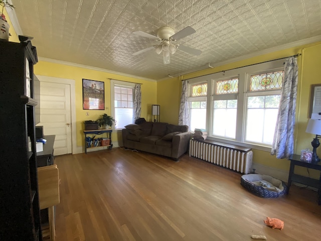 living room featuring radiator heating unit, wood-type flooring, ceiling fan, and ornamental molding