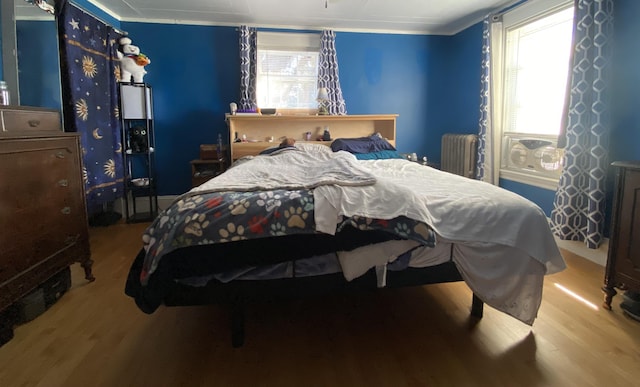 bedroom featuring crown molding, light hardwood / wood-style floors, and radiator heating unit