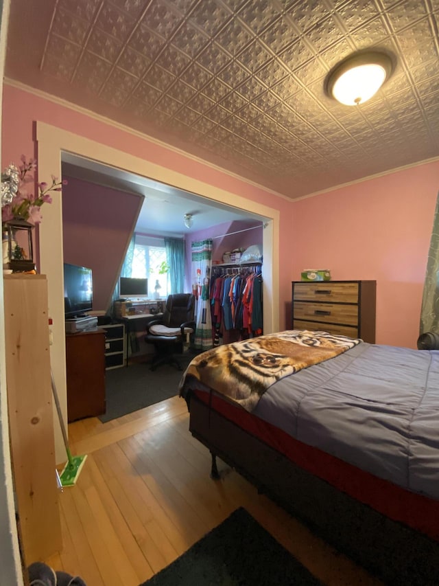 bedroom with ornamental molding, a closet, and hardwood / wood-style floors