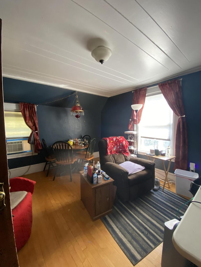 living room with wood-type flooring, lofted ceiling, and cooling unit