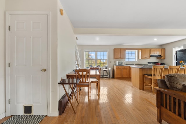 kitchen featuring light wood-type flooring, black fridge, and a breakfast bar area