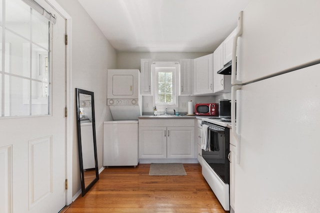 kitchen with sink, white appliances, stacked washer and clothes dryer, white cabinetry, and light hardwood / wood-style floors