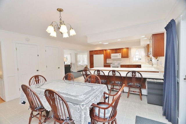 dining space featuring ornamental molding, a chandelier, sink, and a baseboard heating unit