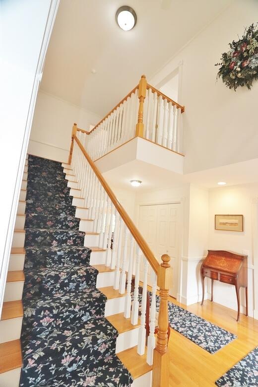 stairway with hardwood / wood-style floors and a high ceiling