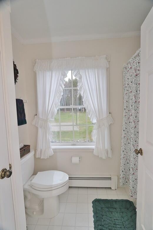 bathroom featuring toilet, ornamental molding, baseboard heating, tile patterned floors, and a shower with shower curtain