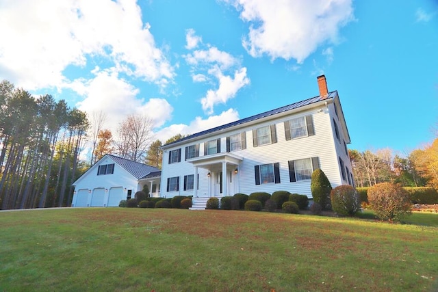 colonial-style house featuring an outdoor structure, a garage, and a front lawn