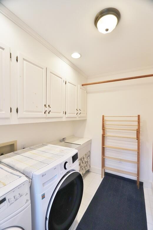 laundry area featuring crown molding, cabinets, separate washer and dryer, and light tile patterned floors