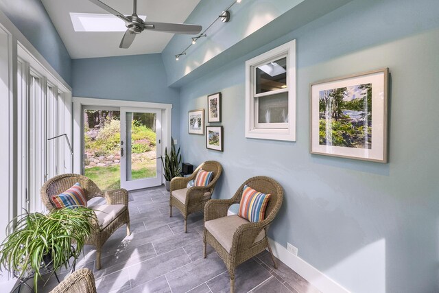 living area featuring lofted ceiling with skylight, ceiling fan, and track lighting