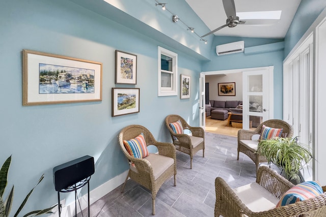 sitting room featuring vaulted ceiling with skylight, ceiling fan, and a wall mounted air conditioner