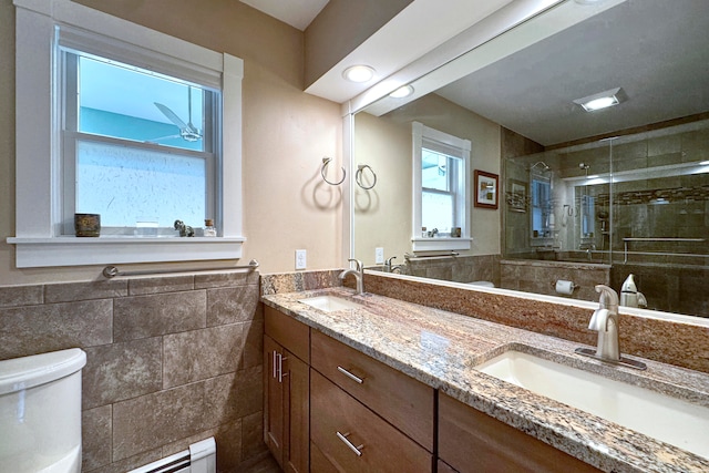 bathroom with tile walls, vanity, toilet, and a shower with door