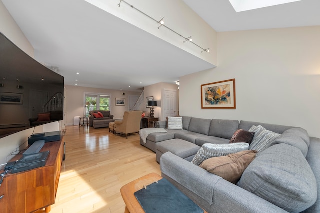 living room with a skylight, light hardwood / wood-style flooring, and rail lighting