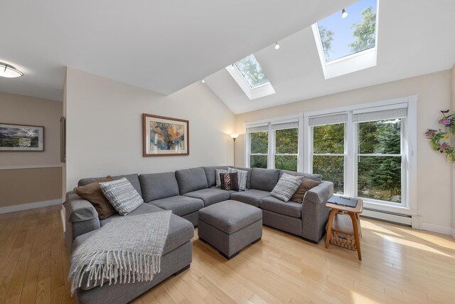 living room featuring light hardwood / wood-style floors, lofted ceiling with skylight, and a baseboard heating unit