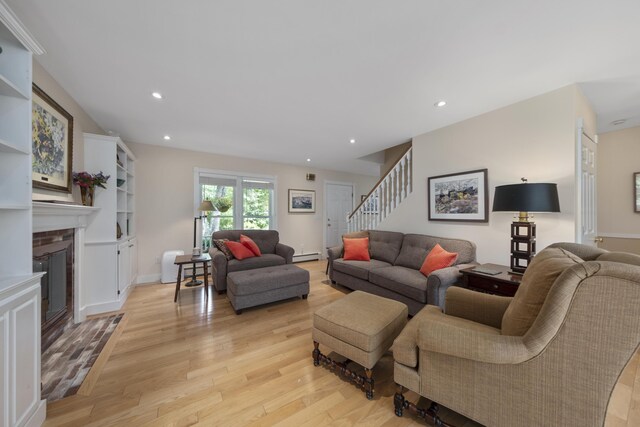 living room with a fireplace, light hardwood / wood-style flooring, and a baseboard radiator