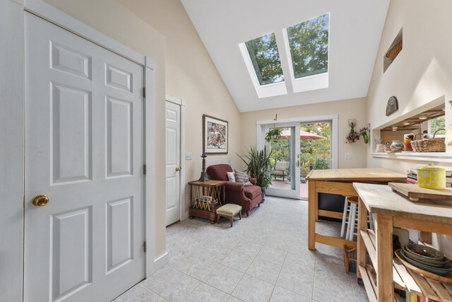 dining room featuring high vaulted ceiling, a skylight, and light tile patterned flooring