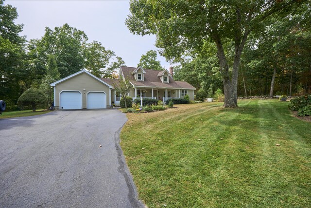 new england style home featuring a front lawn, covered porch, and a garage