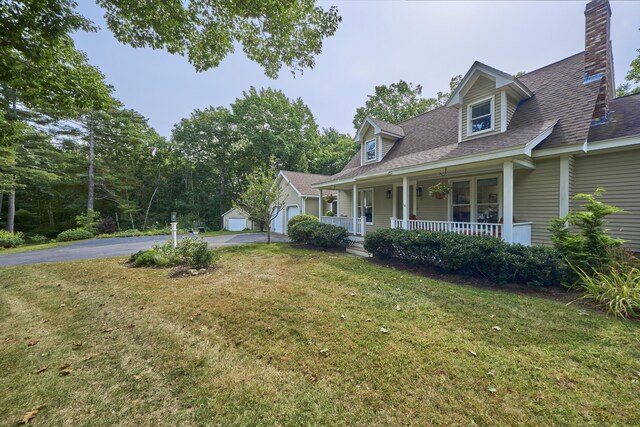 view of home's exterior featuring a garage, an outbuilding, a porch, and a yard