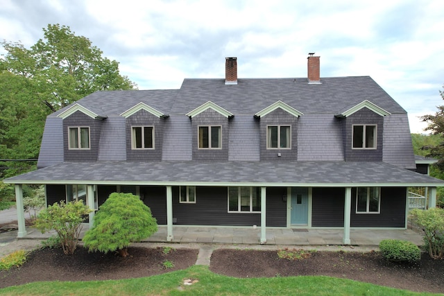 view of front facade featuring a porch, roof with shingles, and a gambrel roof