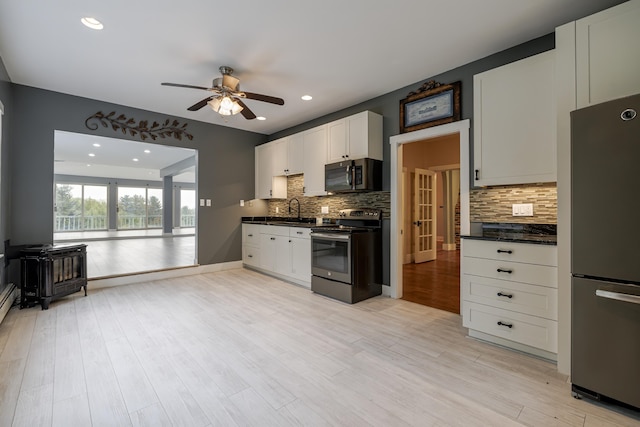 kitchen with stainless steel appliances, a wood stove, ceiling fan, and dark countertops