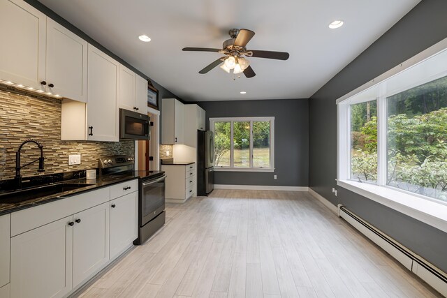 kitchen featuring ceiling fan, tasteful backsplash, a sink, stainless steel appliances, and a baseboard radiator