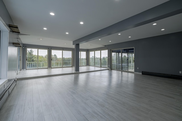 spare room with a healthy amount of sunlight, recessed lighting, wood finished floors, and baseboard heating
