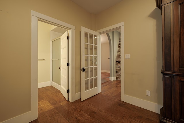 hall with dark wood-type flooring, french doors, baseboards, and arched walkways