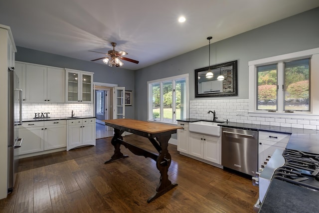kitchen with white cabinets, dishwasher, a sink, dark countertops, and decorative backsplash