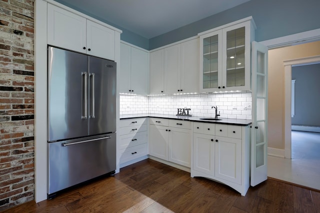 kitchen with white cabinets, sink, brick wall, dark wood-type flooring, and high end refrigerator