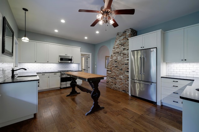 kitchen with white cabinetry, high end appliances, pendant lighting, dark hardwood / wood-style floors, and sink