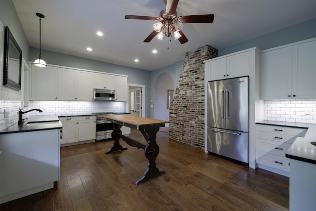 kitchen with high quality appliances, backsplash, a ceiling fan, arched walkways, and a sink