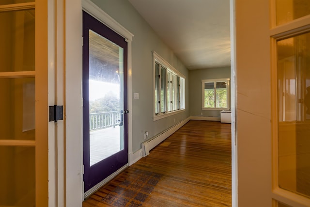 hallway with a baseboard heating unit, baseboards, and wood finished floors