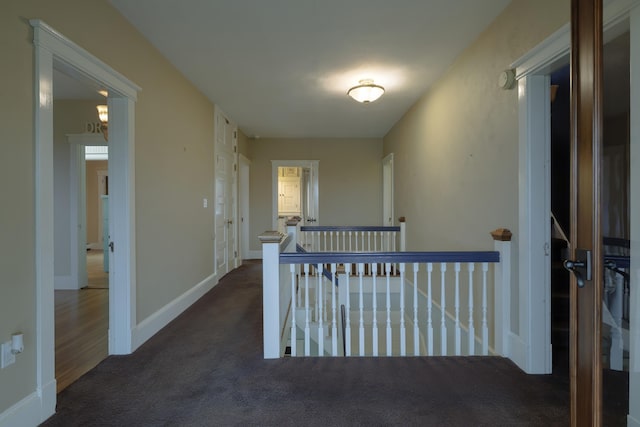 corridor with an upstairs landing, baseboards, and carpet floors
